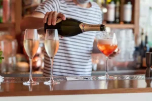 Serveur qui remplit des coupes de prosecco à La Môme Plage 